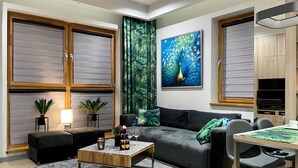 A modern living room with a grey sofa, a wooden coffee table, and a dining area with a table and chairs.