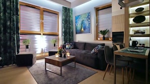 A modern living room with a sofa, coffee table, and dining area.