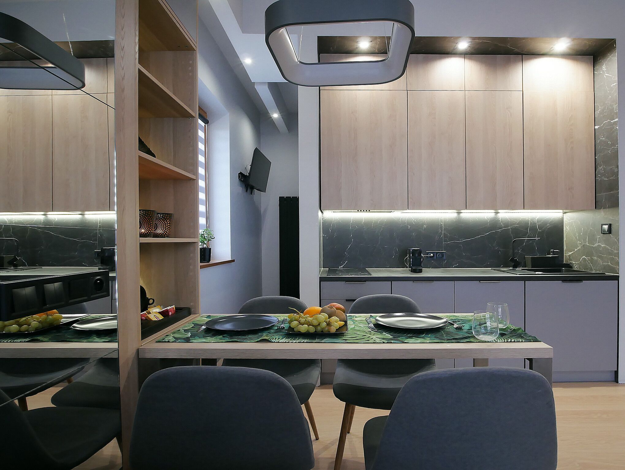 Una cucina moderna con mobili in legno, un piano di lavoro nero e un'area pranzo con un tavolo apparecchiato per due.
