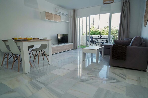 A modern living room with a dining area, a flat-screen TV, and a sofa. - Sunstay Relax 54 Rio Marina Nerja (Nerja)