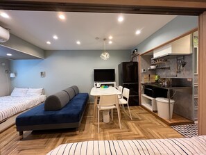 Ein gemütlicher Raum mit Bett, Schlafsofa, Esstisch und Küchenzeile.