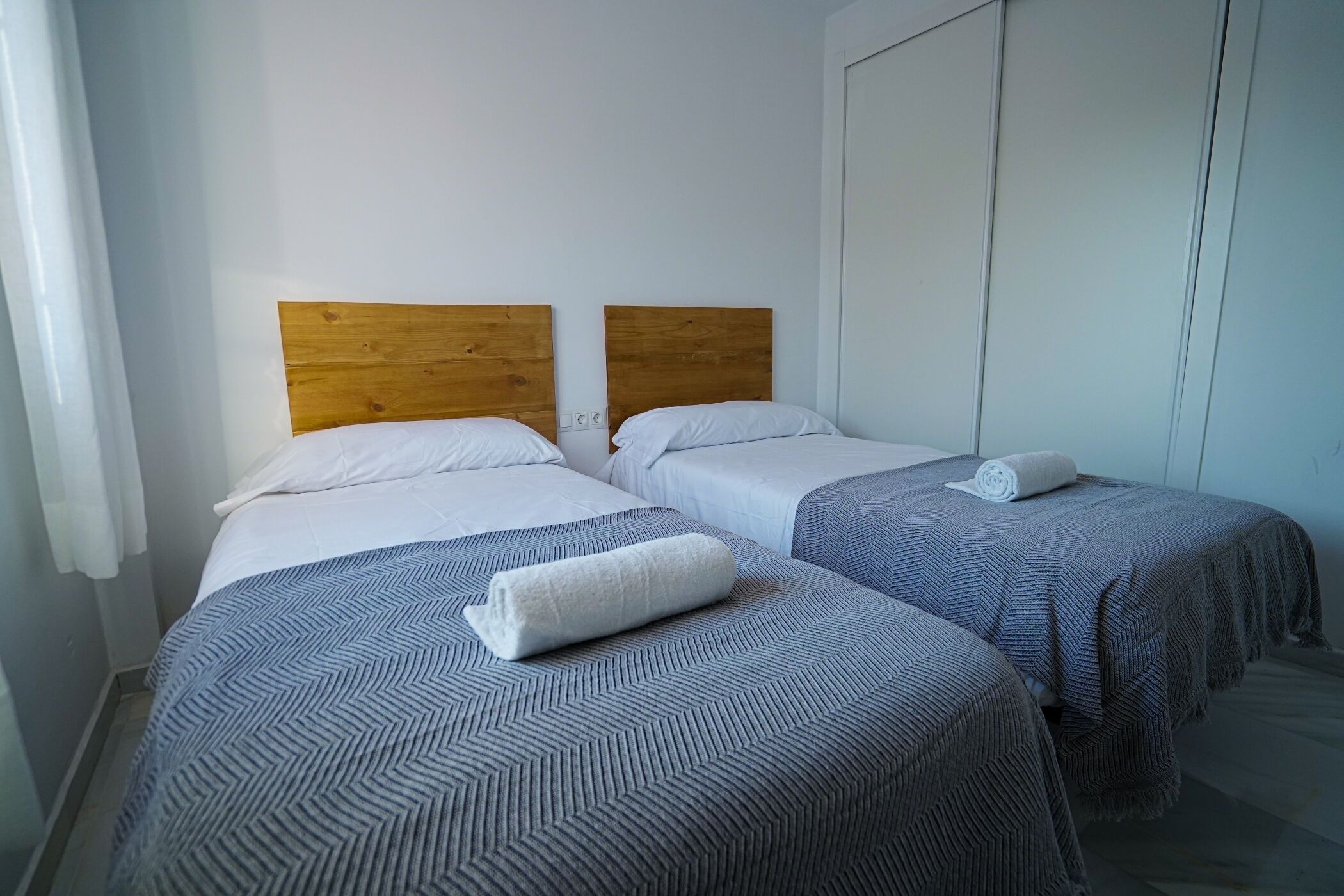 Een hotelkamer met twee bedden, elk met een houten hoofdeinde en een blauw gestreept dekbed.