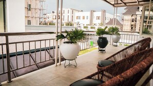 Un balcon agrémenté de fauteuils en osier, de plantes en pot et offrant une vue sur les bâtiments environnants.
