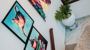 Un escalier agrémenté d’une plante en pot, de trois œuvres d’art encadrées et d’un luminaire fixé au mur.