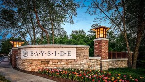 A stone wall with a sign reading "BAYSIDE" and a brick tower with lights.