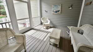 A covered porch with wicker furniture, a bench, and a painting on the wall.