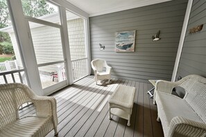 A covered porch with wicker furniture, a bench, and a painting on the wall. - Bayside Resort: New Listing * Fenwick Island * Nex (Selbyville)