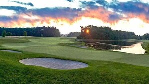 A golf course with bunkers, a pond, and trees.