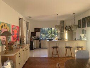 Una cocina moderna con una isla central, taburetes de bar y obras de arte en las paredes.