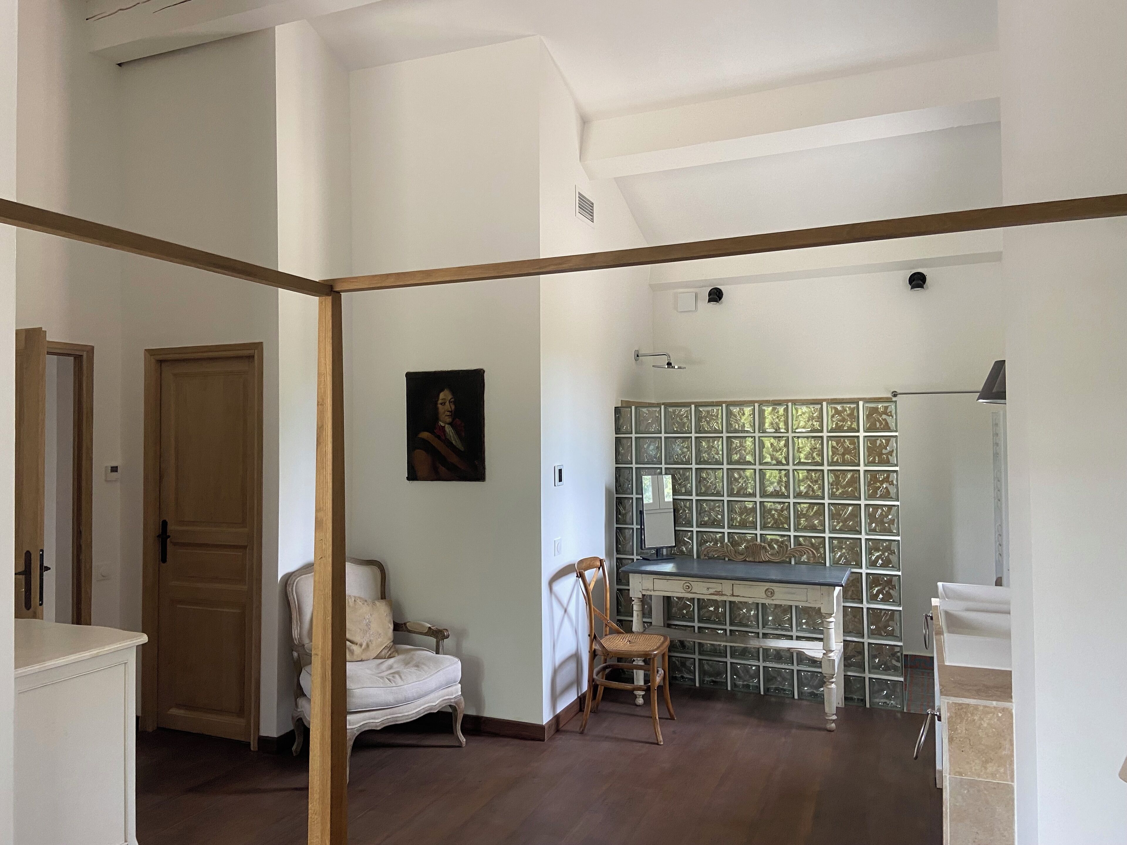 Una habitación con una puerta de madera, una silla blanca, un escritorio y una pared con un panel decorativo.
