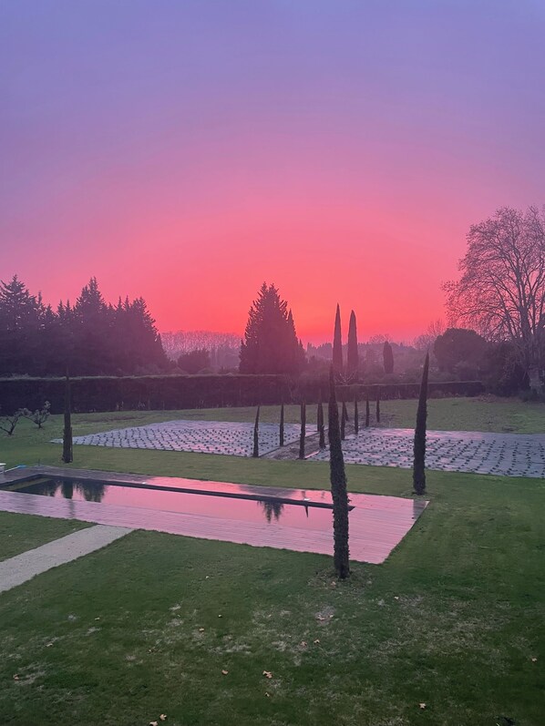 Un parque tranquilo con un estanque que refleja el cielo al atardecer, árboles y entorno relajante.