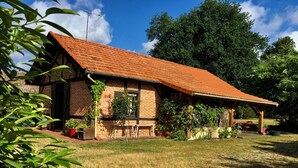A brick house with a red-tiled roof, a covered porch, and a grassy yard. - Maison Clôturée, Plages, Lacs, Océan et Jacuzzi. Animaux de Compagnie Acceptés (Escource)