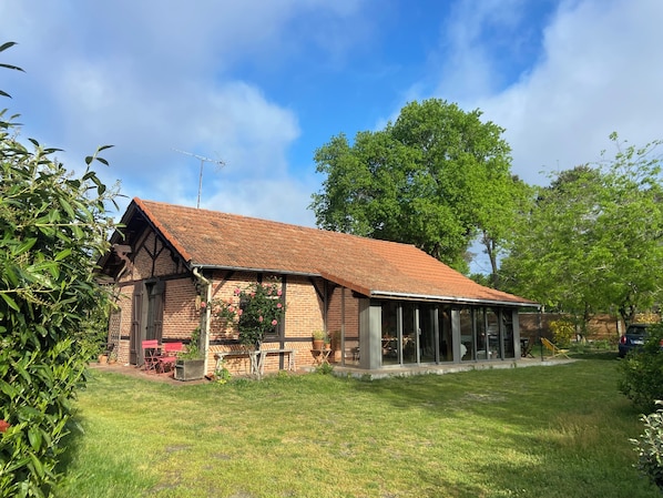A brick building with a sloped roof, a covered porch, and a lawn.