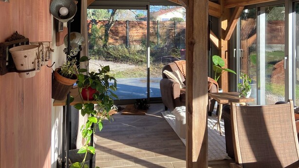 A wooden interior with a large glass door leading outside, wooden beams, and potted plants. - Maison Clôturée, Plages, Lacs, Océan et Jacuzzi. Animaux de Compagnie Acceptés (Escource)