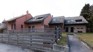 Un bâtiment à deux étages, avec un toit en pierre et une clôture en bois à l’avant.