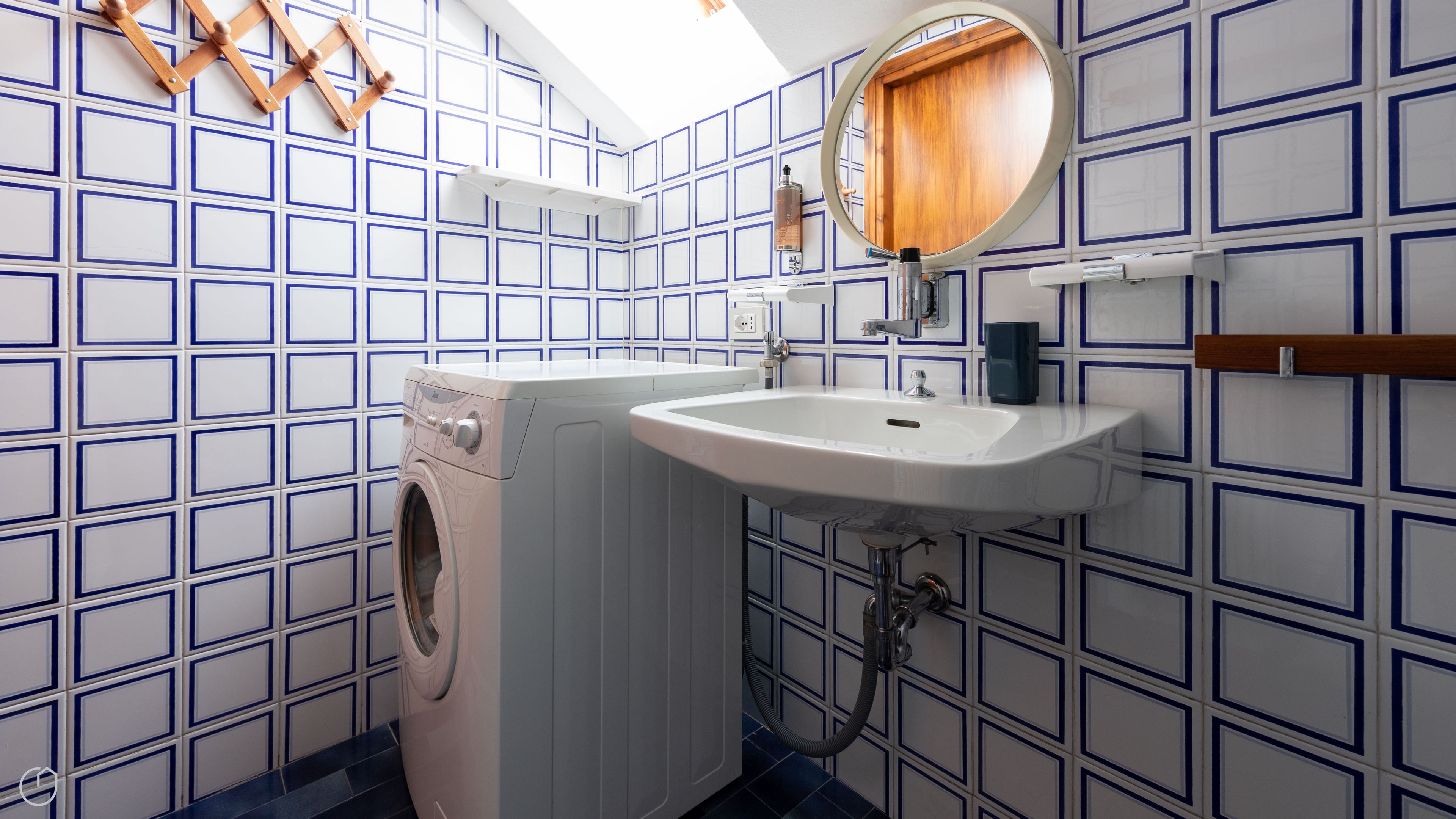 Un baño con lavadora, lavamanos y espejo.