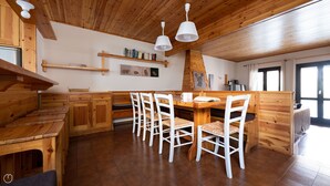 A wooden interior with a dining area, wooden cabinets, and a fireplace. - Italianway - Capitano Grandi 5 (Bormio)