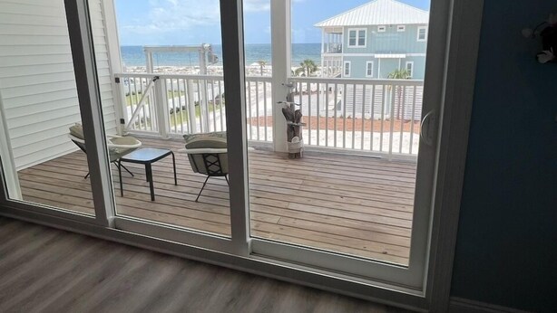 Una habitación con vista a una terraza de madera y una casa al otro lado del agua.