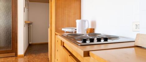 A modern kitchen with wooden cabinets, a built-in stove, and a kettle.