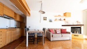 Eine moderne Küche mit Holzausbau, einem Esstisch mit Stühlen und einem Kamin mit Dekoration.
