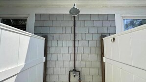 Baño con ducha, paredes de azulejos y tuberías visibles.