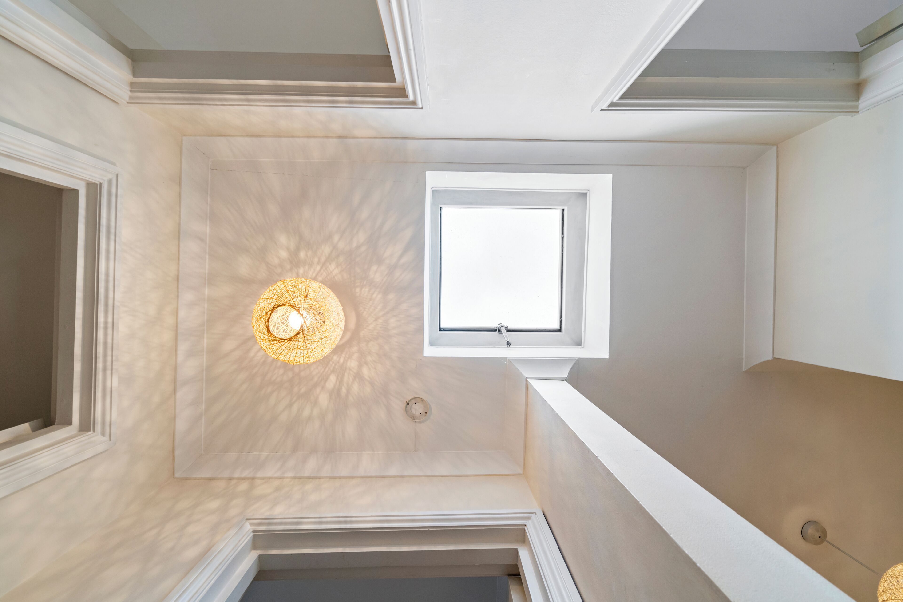 Een kamer met dakraam, hanglamp en raam.
