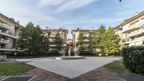 Un patio con una fuente central, rodeado de edificios residenciales de varios pisos con balcones y vegetación.