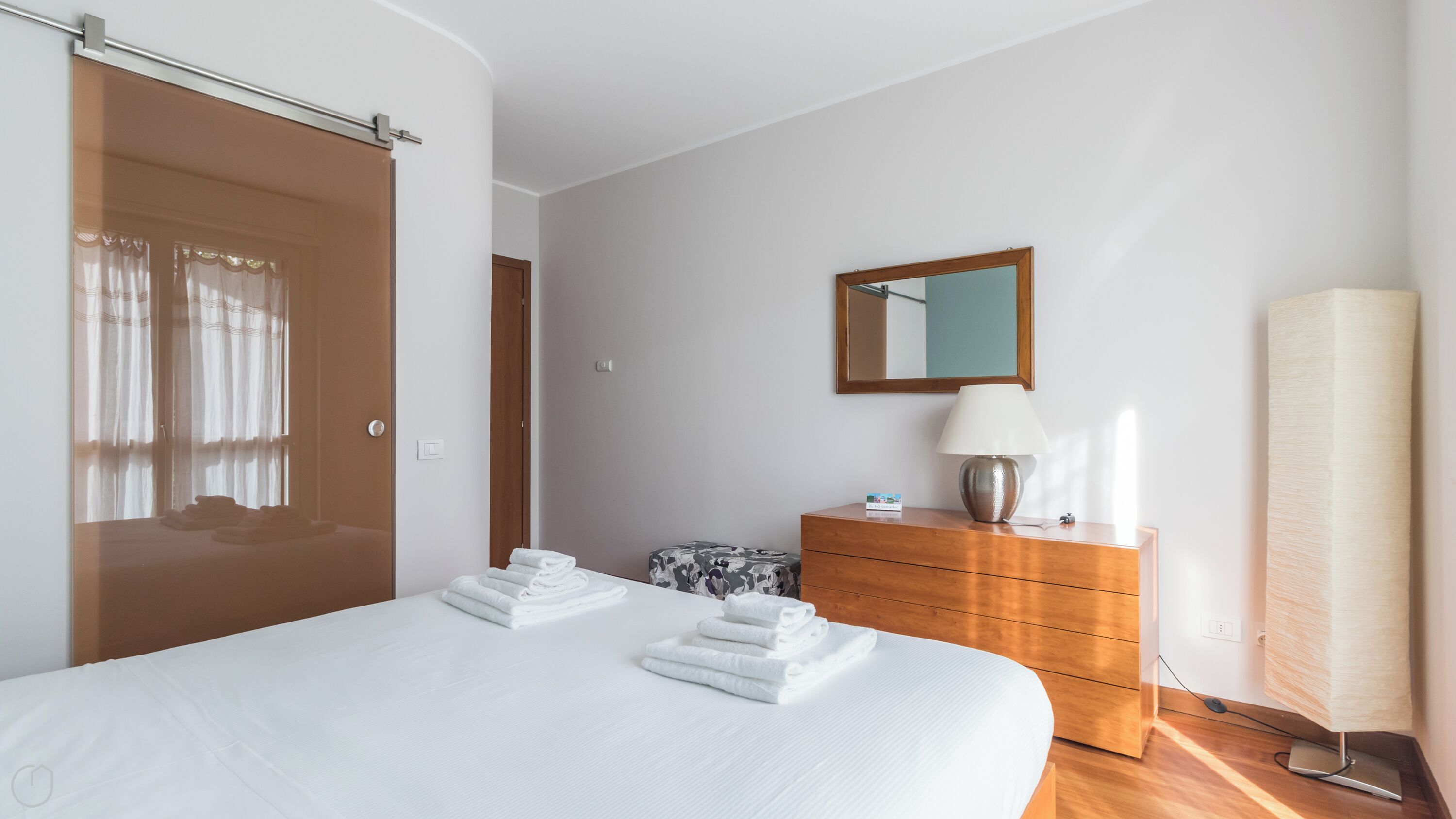 A hotel room with a large bed, a wooden dresser, a mirror, and a lamp.