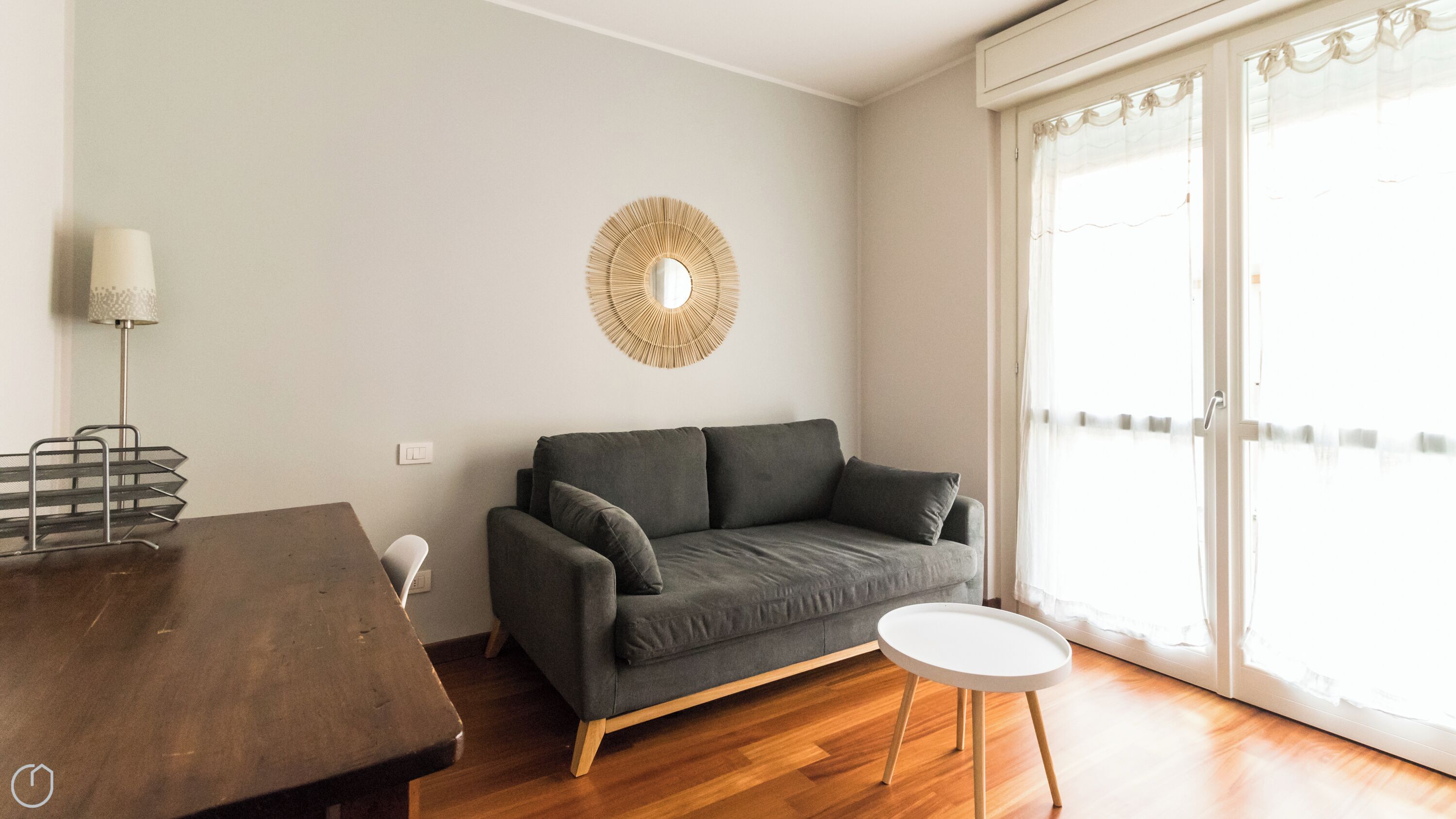 A modern living room with a grey sofa, a small round table, and a lamp.