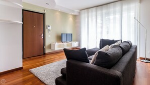 Una sala de estar moderna con un sofá, un televisor y piso de madera.