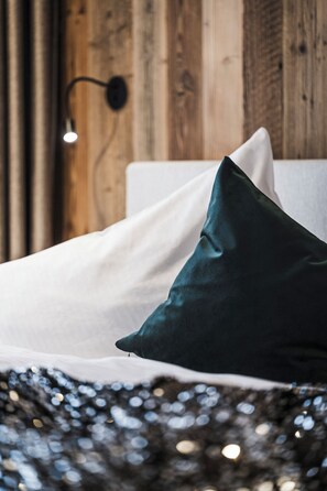 Cozy retreat with a bed featuring a dark green and white pillow arrangement, set against a rustic wooden wall.