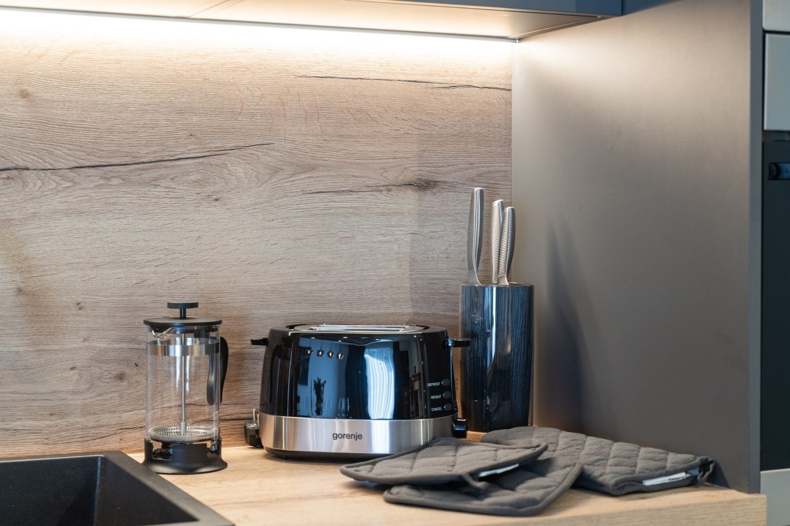 A kitchen with a coffee maker, a glass carafe, and a knife block.