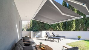 Eine moderne Terrasse im Freien mit einer Couch, Liegestühlen und einem Tisch mit Obst.