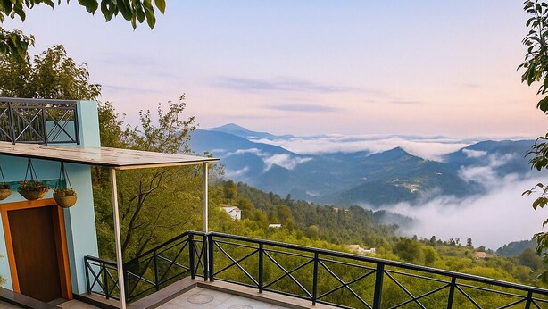 Una terraza con una mesa y sillas, una puerta de madera y vistas a montañas y nubes.