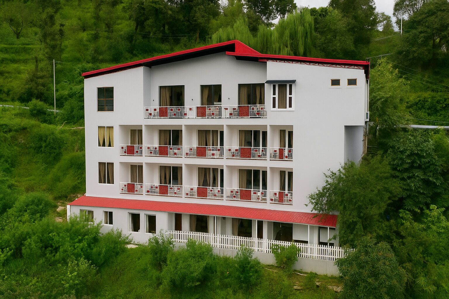 A multi-story hotel with a red roof and white exterior, surrounded by lush greenery.