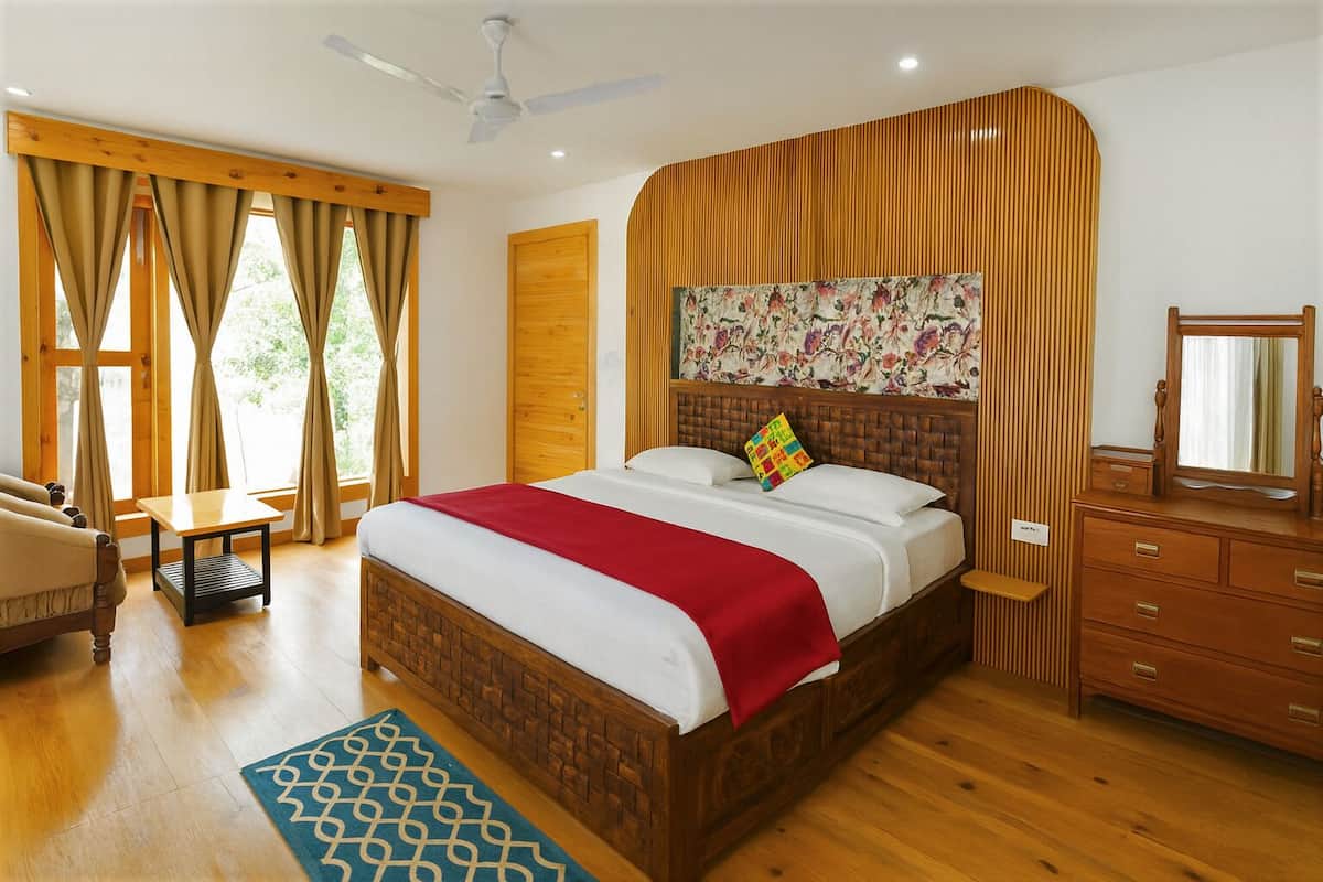 Un dormitorio con una cama de madera, un aparador de madera, un ventilador de techo y una ventana con cortinas.
