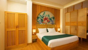 Una habitación de hotel con una cama de madera, dos mesitas de noche con lámparas, una obra de arte floral grande sobre la cama y un armario de madera con puerta de mimbre.