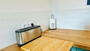 Una cocina con un tostador, un dispensador de toallas de papel y una tabla de cortar de madera sobre la encimera.