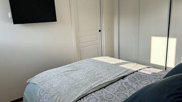 Une chambre à coucher avec un lit, un téléviseur fixé au mur et une porte.