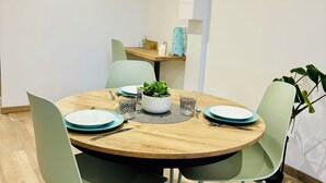 Un comedor con una mesa redonda de madera, cuatro sillas y una planta en maceta.