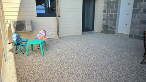 Un área de patio techada con una mesa y sillas, una ventana y una puerta.
