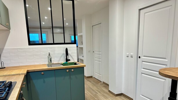 Una cocina moderna con encimera de madera, armarios color turquesa y grifo negro.