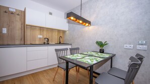 Une cuisine moderne avec des meubles blancs, un plan de travail en bois et un coin repas comprenant une table et des chaises.