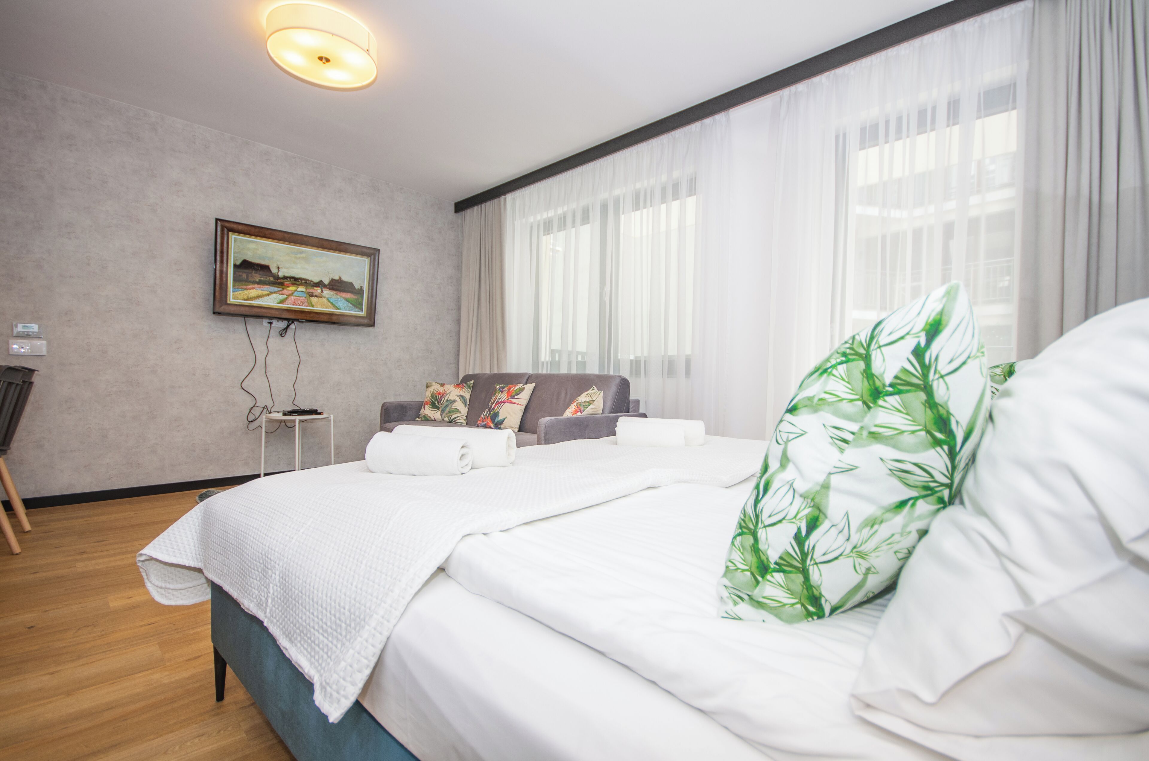 Una habitación de hotel moderna con una cama grande, una mesita auxiliar, una silla y un cuadro en la pared.