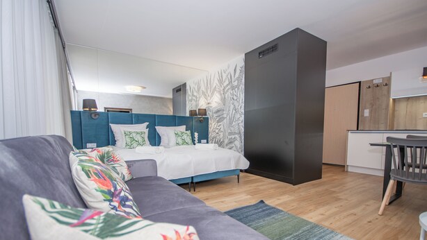 Une chambre d’hôtel moderne équipée d’un lit, d’un canapé, d’un bureau et d’une kitchenette.