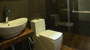 Un baño con lavamanos blanco, inodoro y cabina de ducha de vidrio.