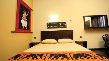 A hotel room with a bed, a wall-mounted light, a decorative wall piece, and a chair.