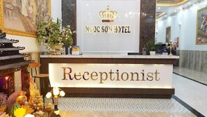 A reception desk with a sign reading "NGOC SON HOTEL" and "Receptionist".