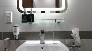A bathroom with a white sink, a mirror, and a glass shelf.