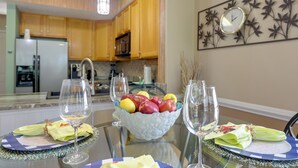 A dining table set with a fruit bowl, wine glasses, and napkins.